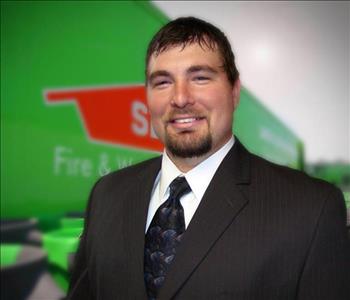 Man in suit with a SERVPRO trailer backdrop in the background